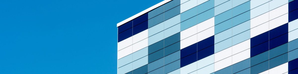 A modern building facade with geometric blue patterns against a clear sky, showcasing contemporary architecture.